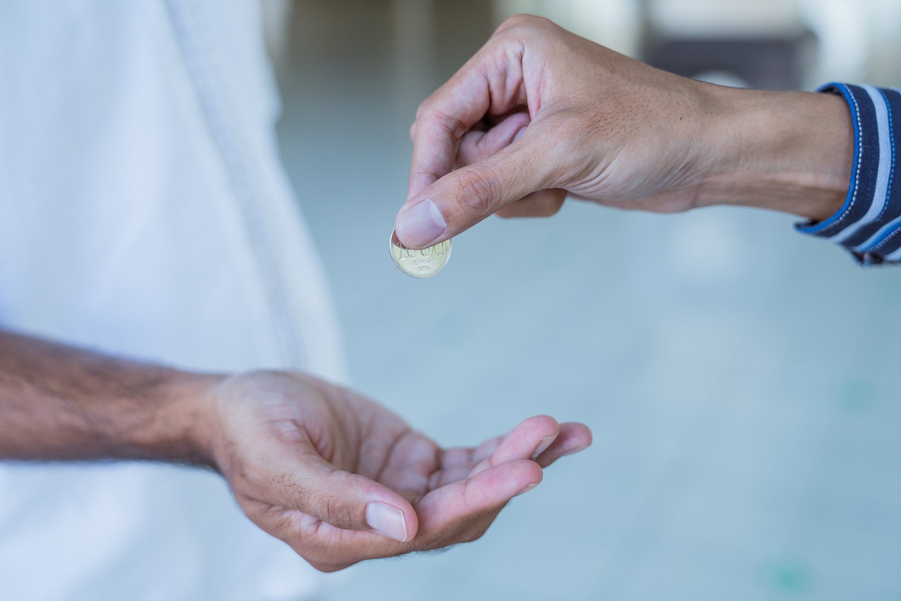 hand giving some money to someone at the mosque